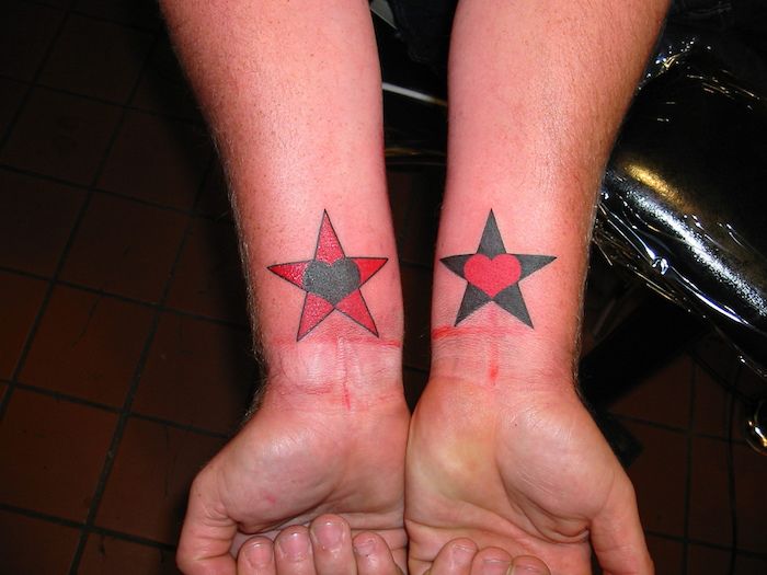 una stella morta con un cuore nero e una stella nera con un cuore rosso - mani e tatuaggio stella
