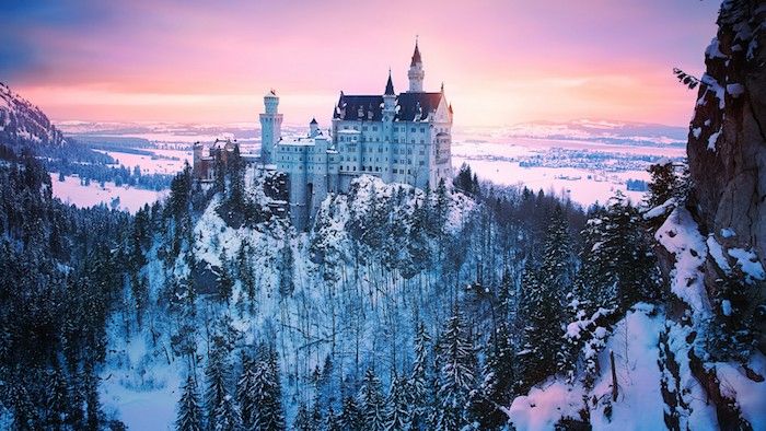 un grande castello bianco nel tramonto - foresta con neve e alberi - cielo con nuvole rosa