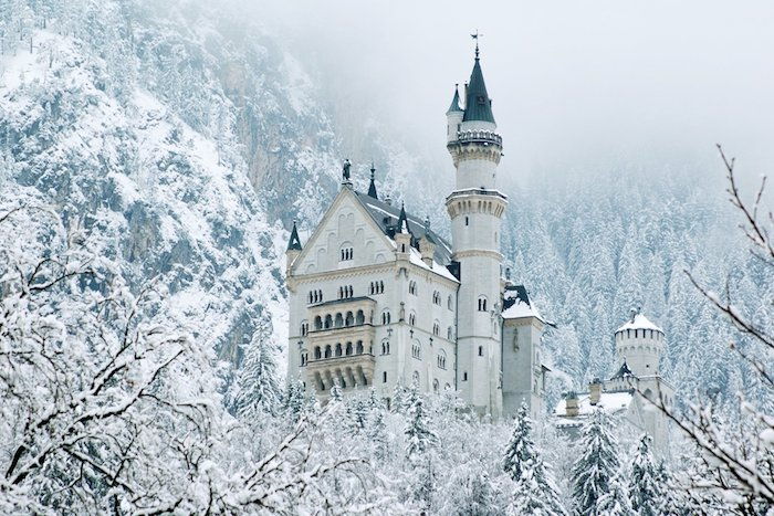 un grande castello bianco con grandi torri - una foresta invernale con alberi e neve