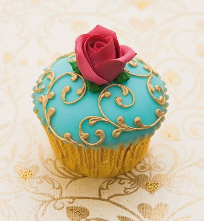 muffin met blauwe fondant met gouden elementen en rode roos