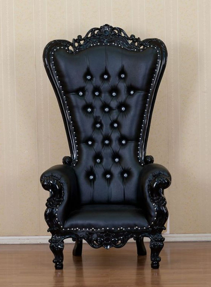 Fotelj v črno barvanem usnju z veliko leseno hrbtno stranjo, kovinske kape