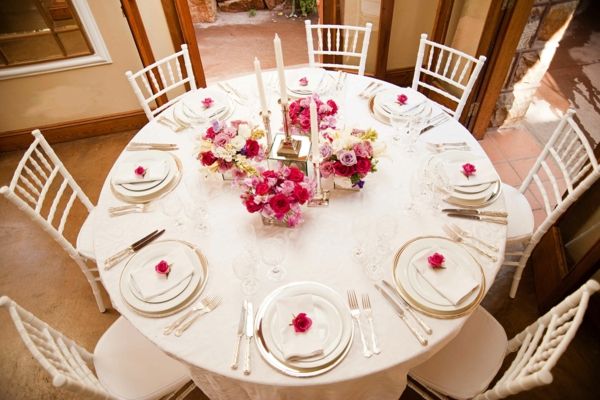 pavasario-vestuvių stalo rožės, raudonos ir rožinės ir baltos žvakės ir baltos kėdės