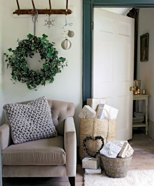 białe świąteczne dekoracje - biały fotel i zielony wianek nad nim