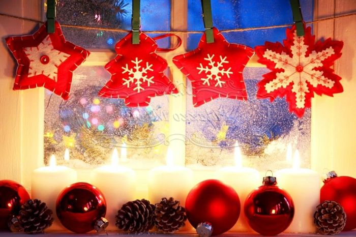 Snowflake i hvitt og rødt bomull, dekorert med en rød glassperle i sentrum, to stjerner i hvitt og rødt, lite juletre laget av rød bomull med et snøfnugg laget av hvit bomull, tre røde julekuler med blankt belegg, to røde julekuler med Matt belegg, fem tente stearinlys hvite stearinen og fire kjegler, røde jule dekorative elementer, hengt på vinduet med en hyssing og grønne tre klesklyper