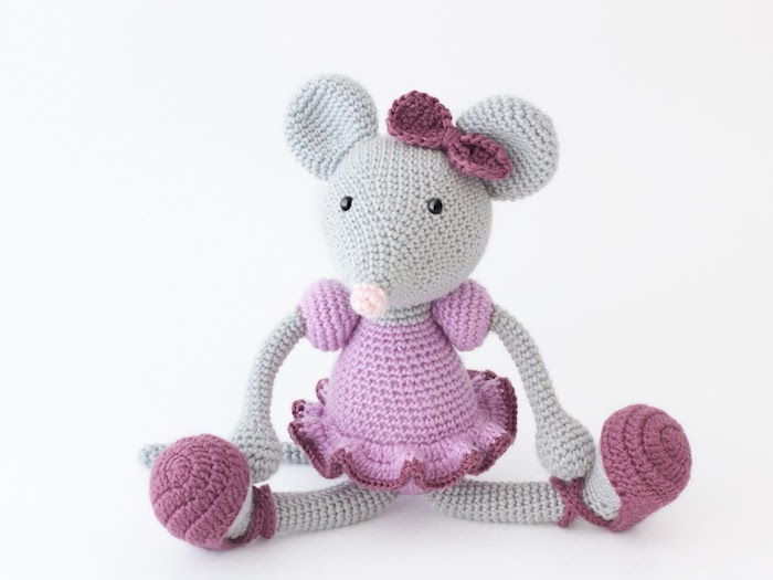 um rato cinza com vestido rosa e crochê com uma pequena fita rosa amigurumi