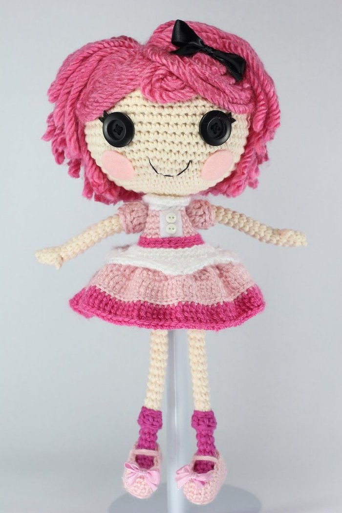 Crochê amigurumi - uma boneca rosa com olhos de botão preto e bochechas rosadas