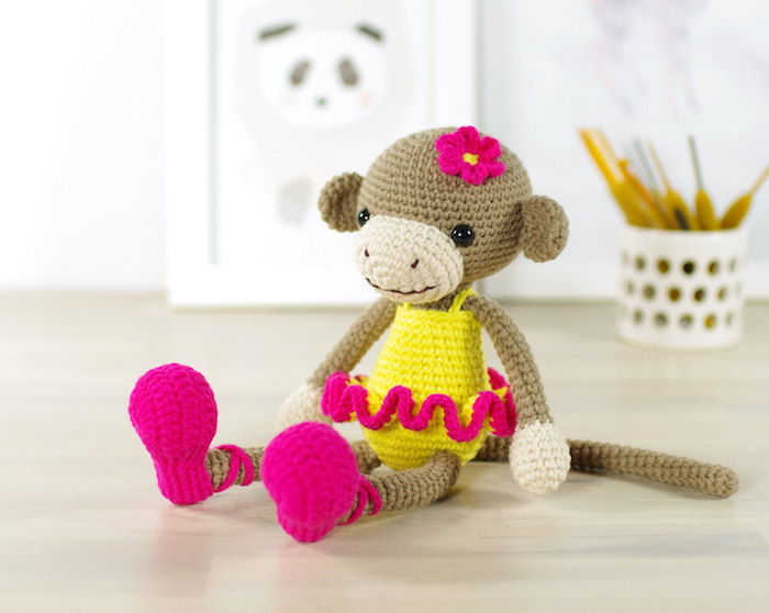 uma menina macaco com roupas amarelas com sotaque rosa e flores na cabeça - padrão de crochê Amigurumi