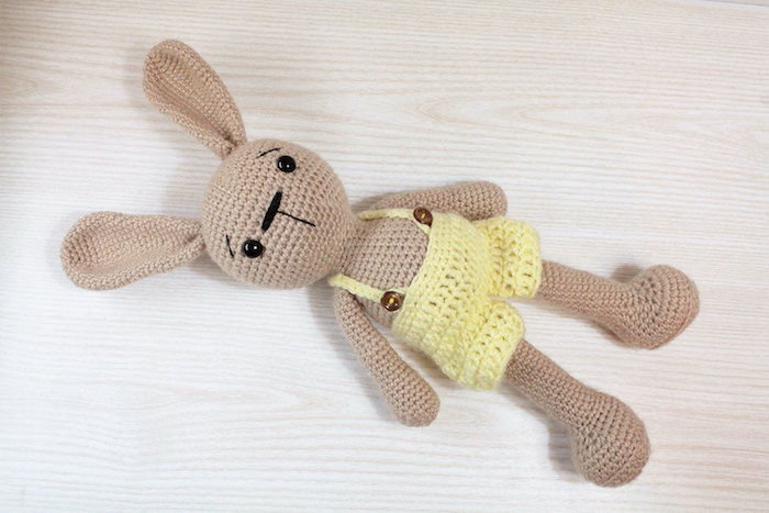 Um coelho marrom com calças amarelas com botões - padrão de crochê Amigurumi
