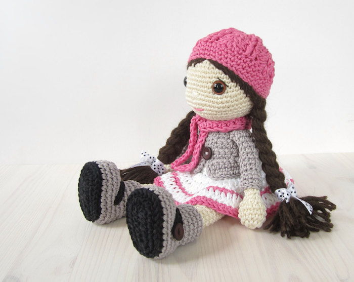 um boneco bonito com lenço rosa e chapéu, longas tranças marrons amigurumi crochet padrão