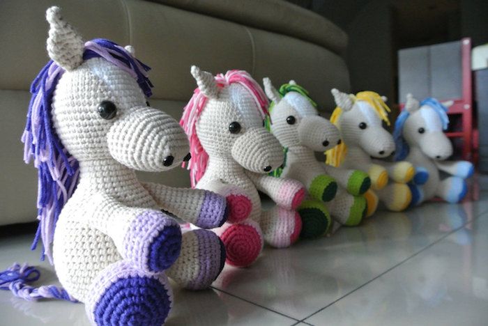 cavalos coloridos dispostos em uma fileira com manes em cores diferentes - padrão de crochê Amigurumi