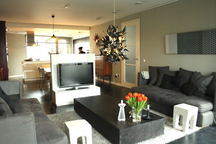 tv-vegg kreativ design i midten av stuen designbordet to sofaer og friske tulipaner på kjøkkenbordet på den andre siden