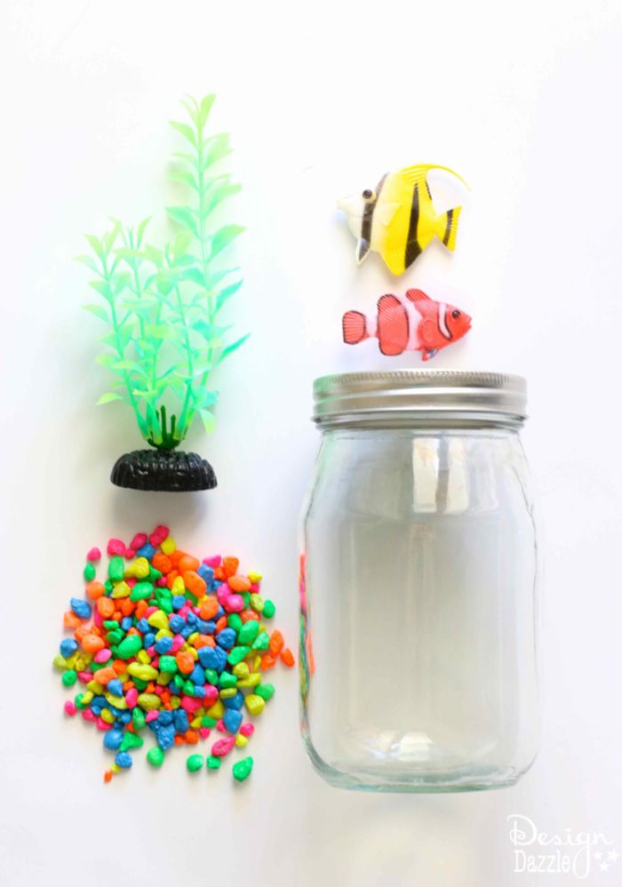 Samotné akvárium, materiály: sklo, farebné dekoratívne kamene, malé ryby a plastová morská tyč