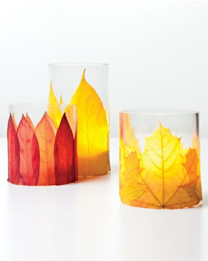 Szklany świecznik ozdobiony jesiennymi liśćmi w różnych kolorach