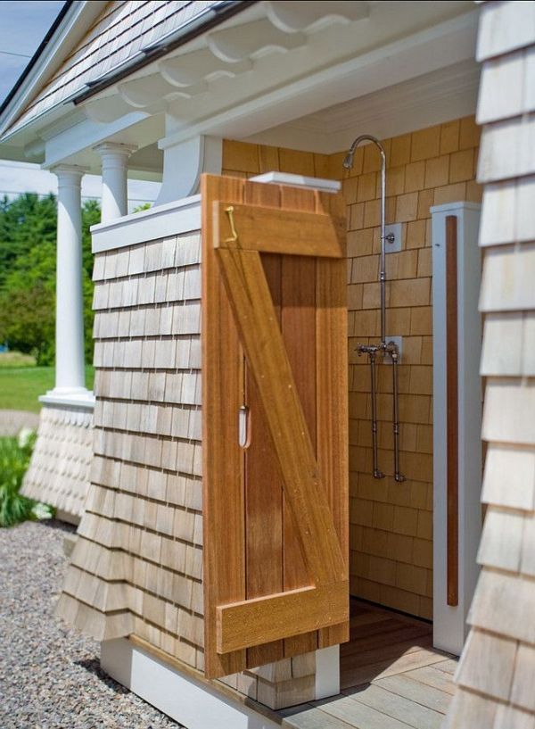 Drevená sprchová kabína pred domom s drevenými dverami