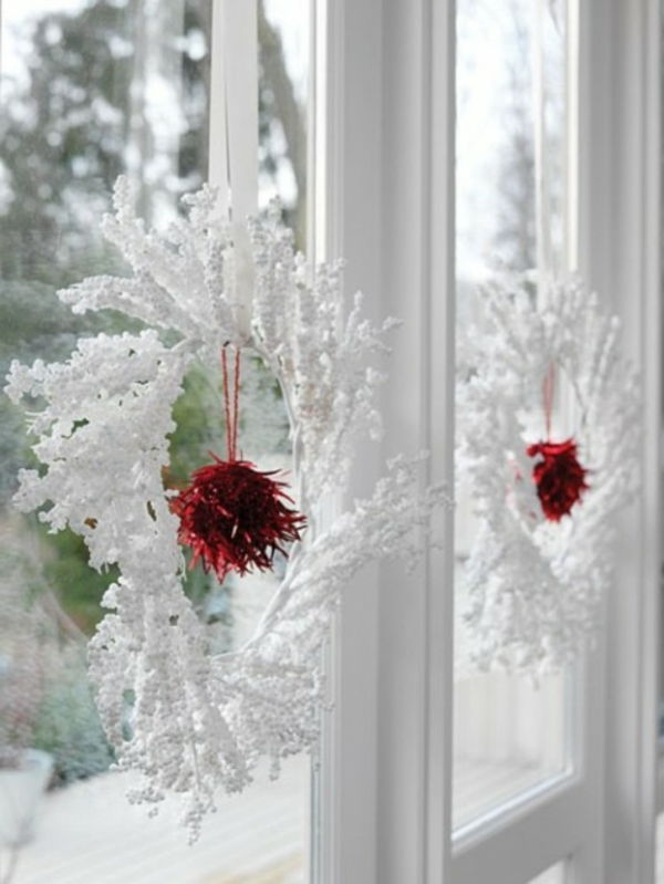 białe świąteczne dekoracje - okno z białymi wieńcami na nim