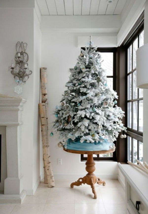 białe świąteczne dekoracje - szklana ściana i choinka obok niej