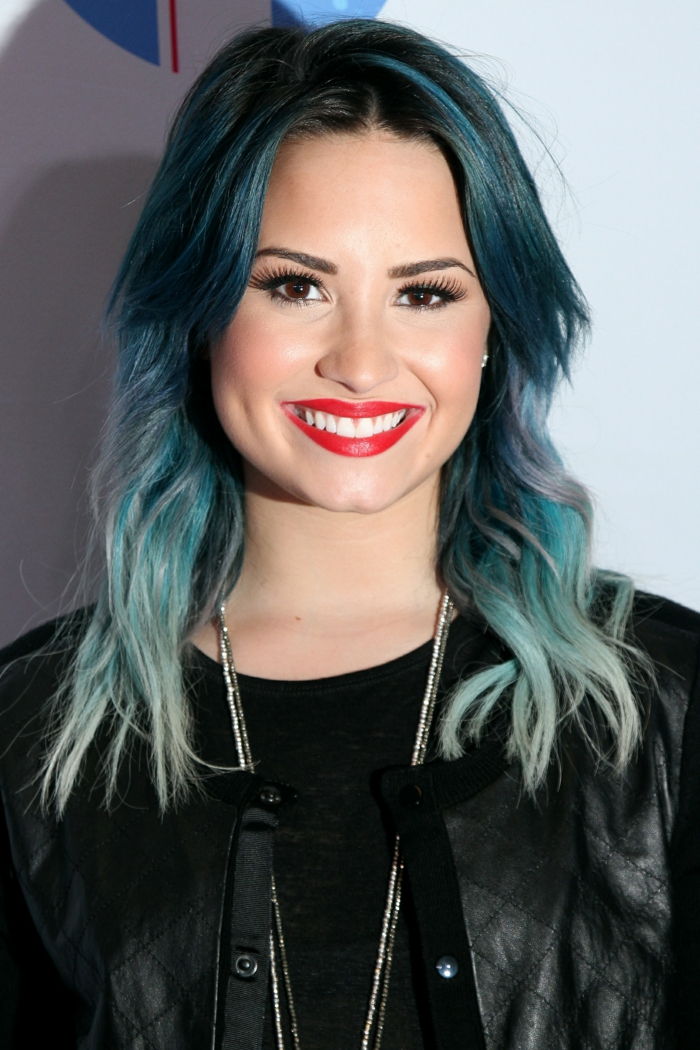 Modré vlasy, Demi Lovato, jasne červené pery, čierne očné linky a maskara, čierna kožená bunda