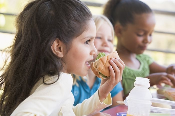 tre små jenter av forskjellig opprinnelse spiser sammen under pause