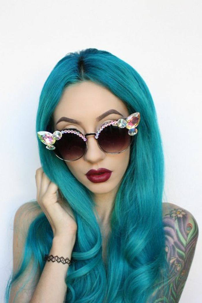 modré vlasy, víno červené pery, porcelánový odtieň, extravagantné slnečné okuliare s kryštálmi, tetovanie na ramene