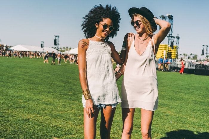 hippie festivalové oblečenie Dve krásne ženy sa bavia na zelenom poli počúvajúc hudbu a teší