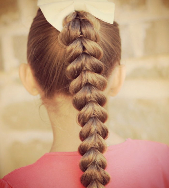 świąteczne fryzury dla dzieci, dziewczyny z oplataną fryzurą z dużą ilością opasek do włosów i białą kokardką