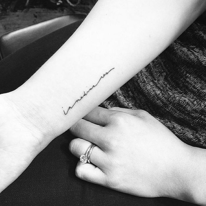 Un alt tatuaj negru mic pe încheietura mâinii unei tinere - o idee pe tema încheierii tatuajului