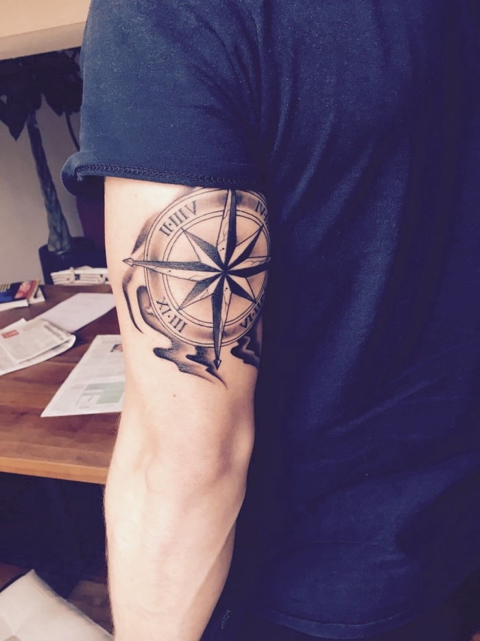 čia yra vyras su dideliu juodos kompaso tatuiruote ant jo rankos - tatuiruotės idėja su kompasu vyrams