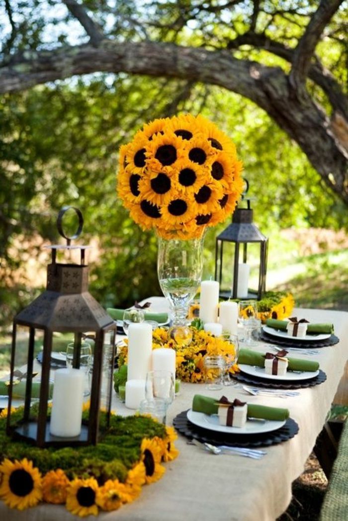 šventinė stalo apdaila, sodo vakarėlis, žibintai, saulėgrąžos, didelio stiklo vaza, nedidelės dovanų dėžutės
