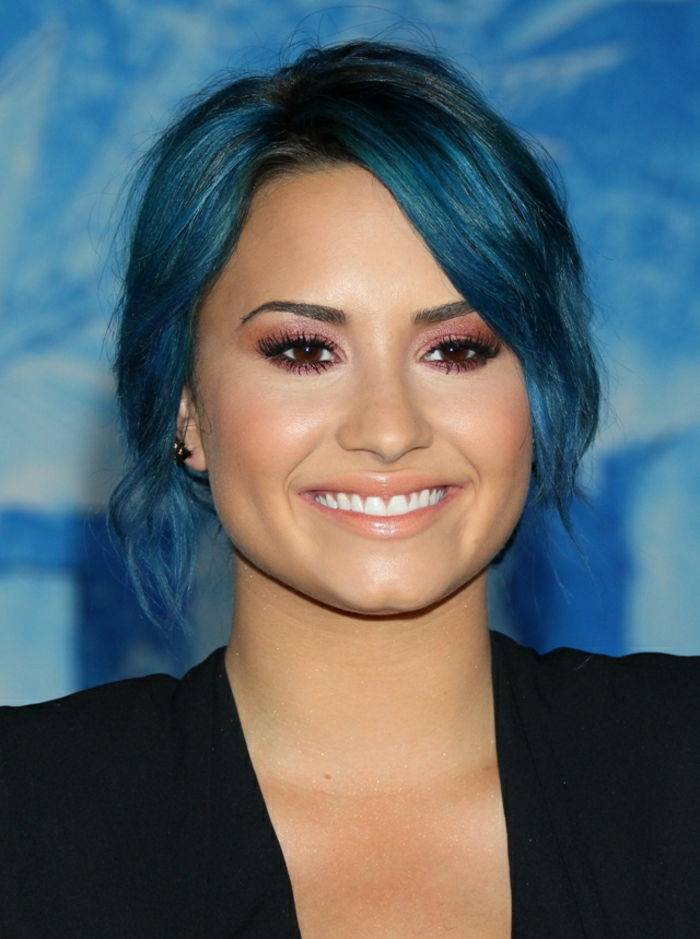 Demi Lovato, modré vlasy, broskyňová rúž, ružový a očný tieň, olivová koža, čierne sako