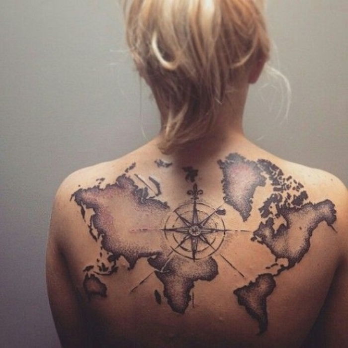 juodas kompasas ir pasaulio žemėlapis - modernios tatuiruotės idėja jaunos moters gale