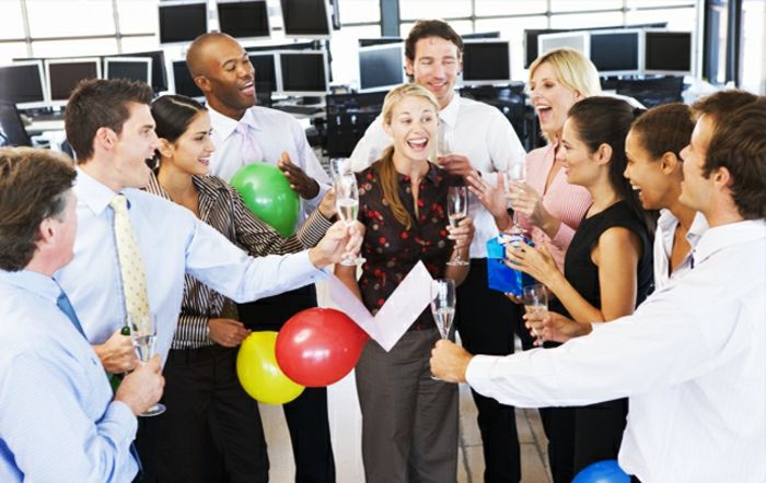 Vestido de código festivo elegante no escritório com os colegas comemorando balões e sorrindo champanhe