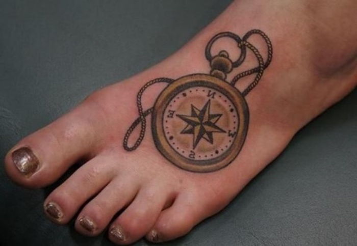 Štai tatuiruotės ant kojos idėja - kojos su nagų lako ir tatuiruotė su auksiniu kompasu