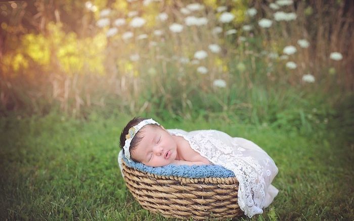 buone foto notturne - ecco un piccolo bambino addormentato con un vestito bianco e un giardino con molte piante verdi e fiori bianchi e gialli