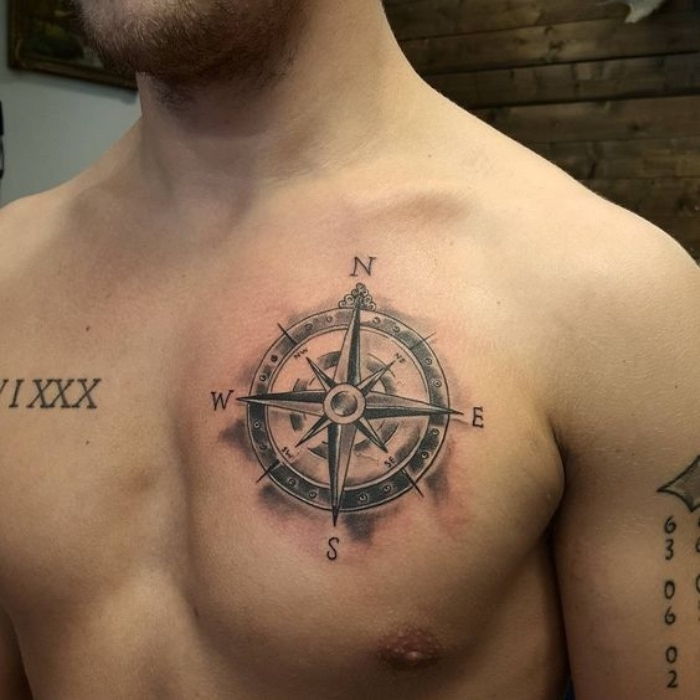 Här visar vi dig en ung man med en stor svart tatuering med en svart kompass - idé för kompasstatuering
