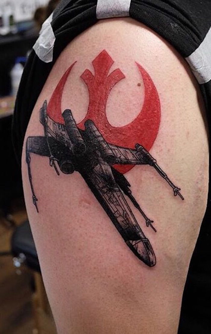 Ruka držiaca veľké tetovanie hviezdnych vojen s lietajúcou čiernou hviezdou vojenskej kozmickej lode a červeným hviezdnym vojenským logom
