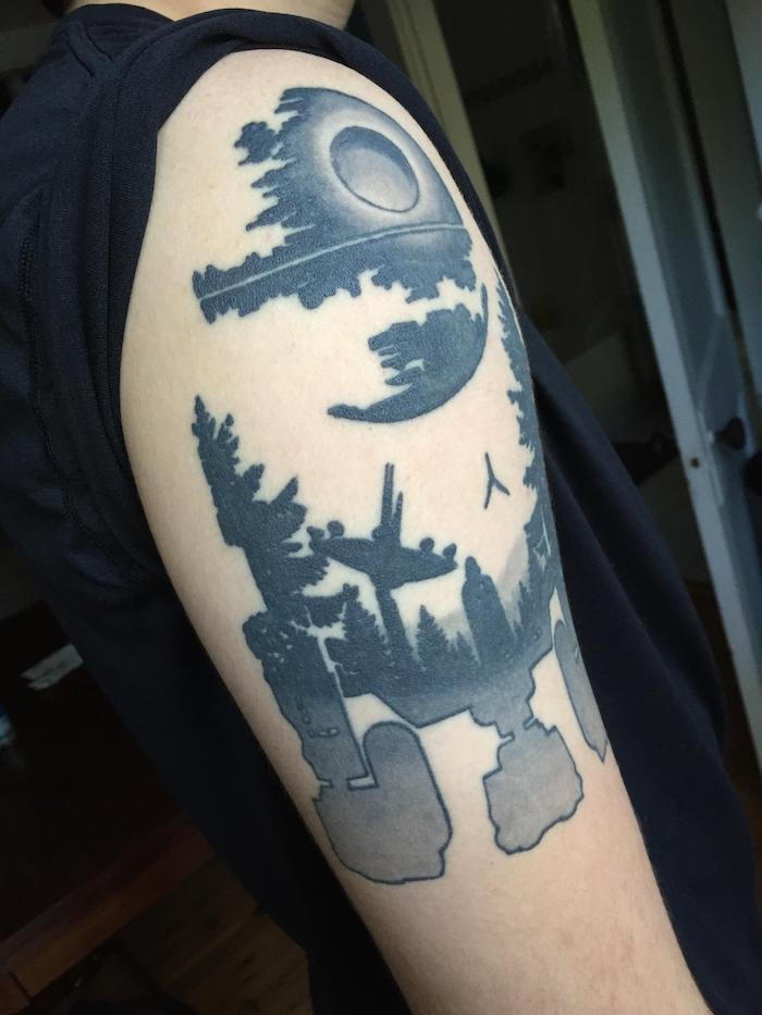 ruka s veľkými tetovanými hviezdnymi vojnami - biely robot - les s čiernymi stromami - darth vader a lietajúca malá čierna loď
