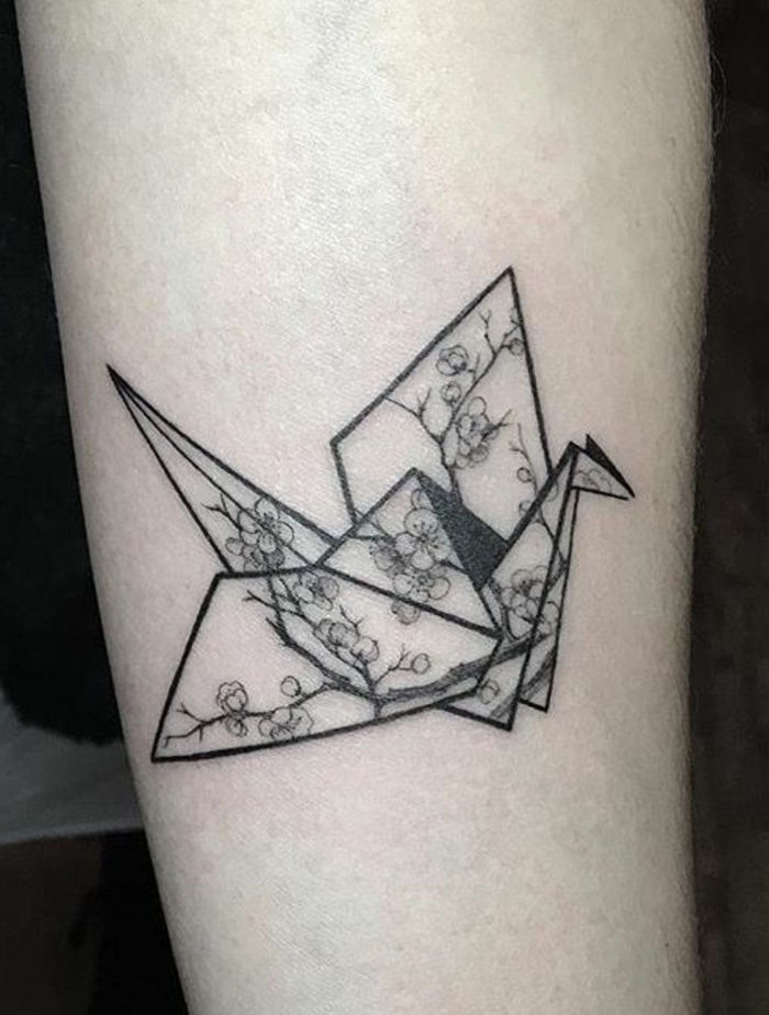 tutaj znajdziesz pomysł na tatuaż origami - latający czarny ptak origami z małymi białymi kwiatami