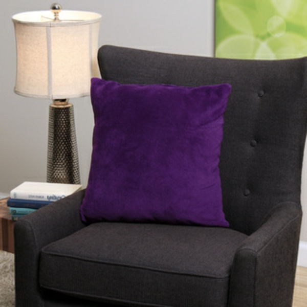 juoda fotelis su mesti pagalvę violetiniu šalia žibinto