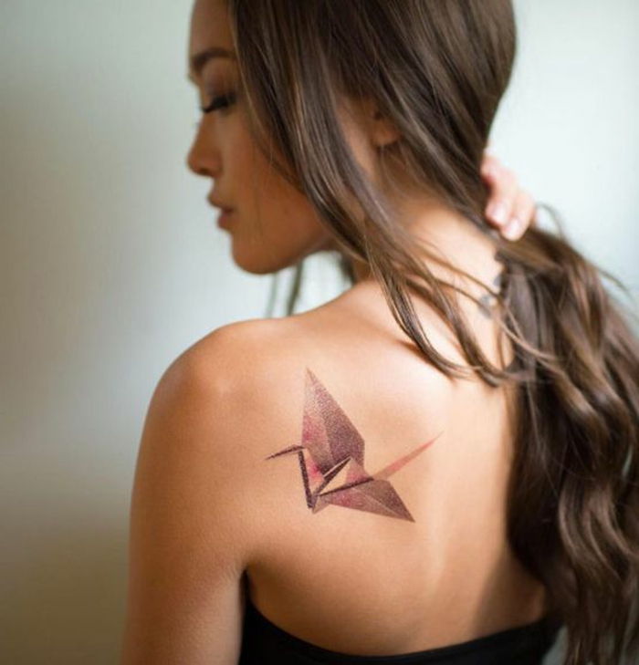 Oto młoda kobieta z tatuażem origami na łopatce - tatuaż origami z czerwonym latającym ptakiem origami