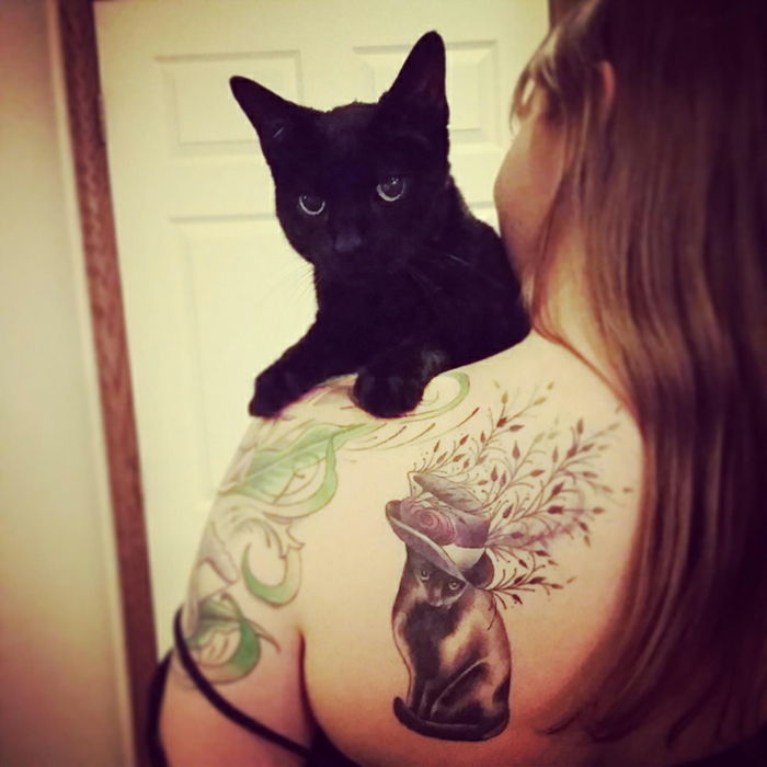 Tutaj znajdziesz pomysł na tatuaż dla kota - tu jest czarny kot i kobieta z tatuażem na ramieniu z czarnym kotem, kapeluszem i roślinami