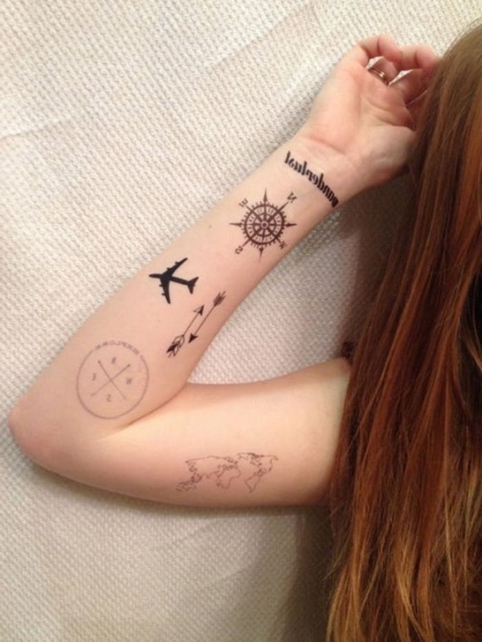 Här är en ung kvinna med en hand med små svarta tatueringar - världens karta, flygväv och två små svarta kompasser