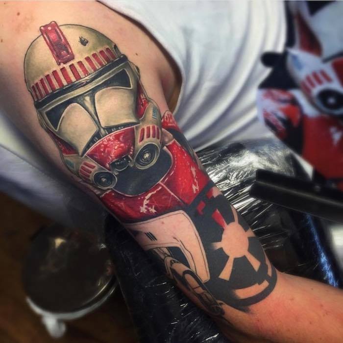 Muž s rukou drží hviezda vojny tetovanie s červeným robotom a malé čierne hviezdy wars tetovanie