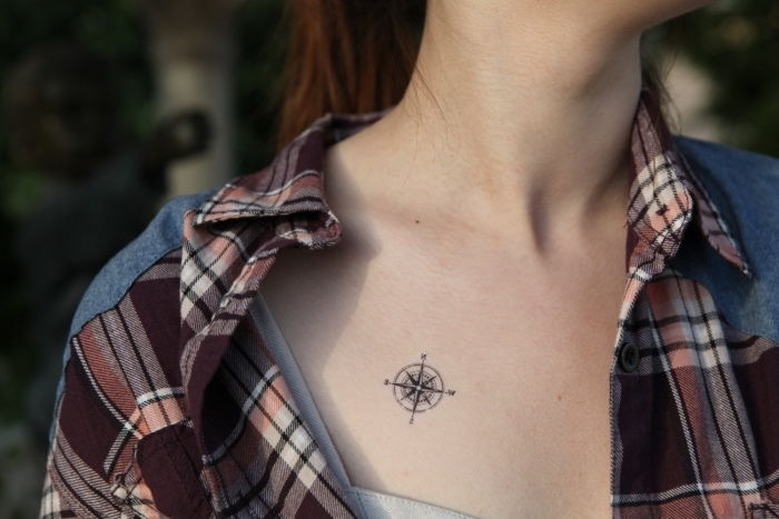 Her kan du se en ung kvinne med en skjorte og en liten svart tatovering med et svart kompass