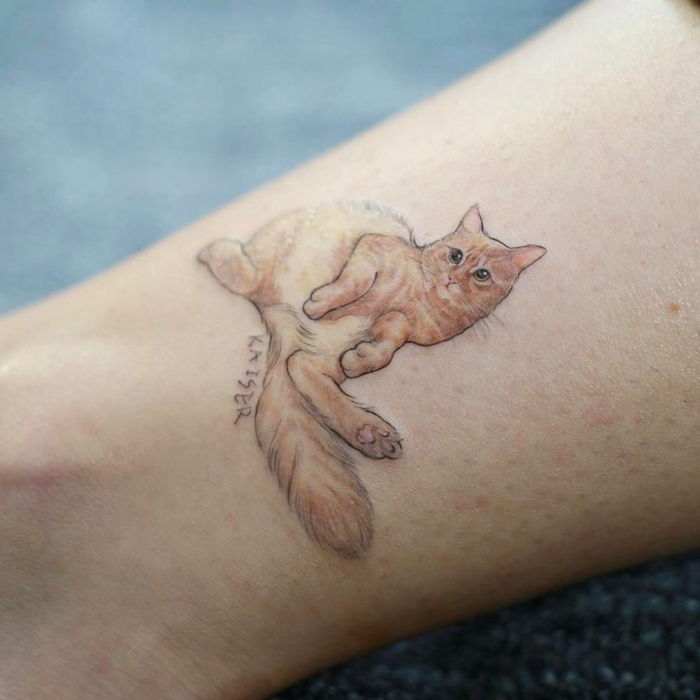 ręka ze wspaniałym tatuażowym kotem - oto pomarańczowy kot z dużymi czarnymi oczami