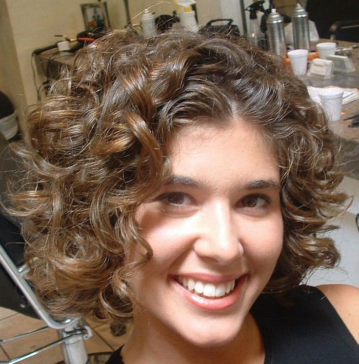 en jente med et vakkert smil som presenterer korte frisyrer for krøllete hår