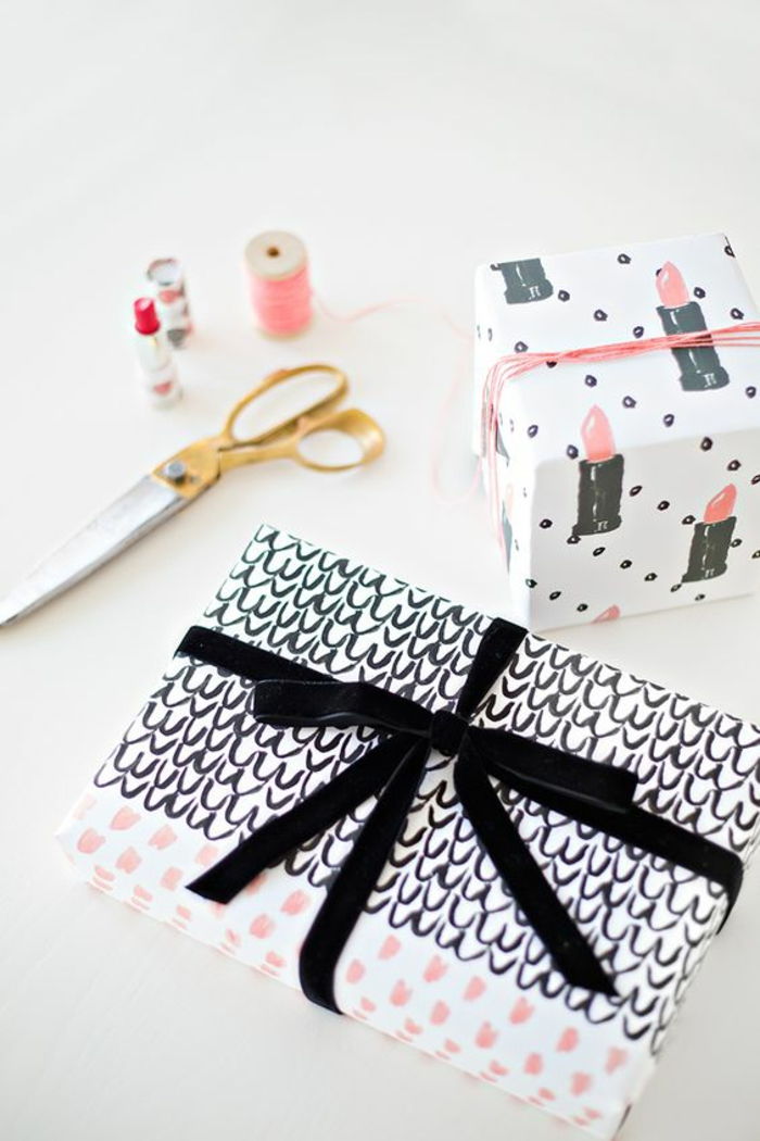 Gjør gavepakke - svart bånd med malt mønster og en annen gave med leppestifttegninger på innpakningspapir