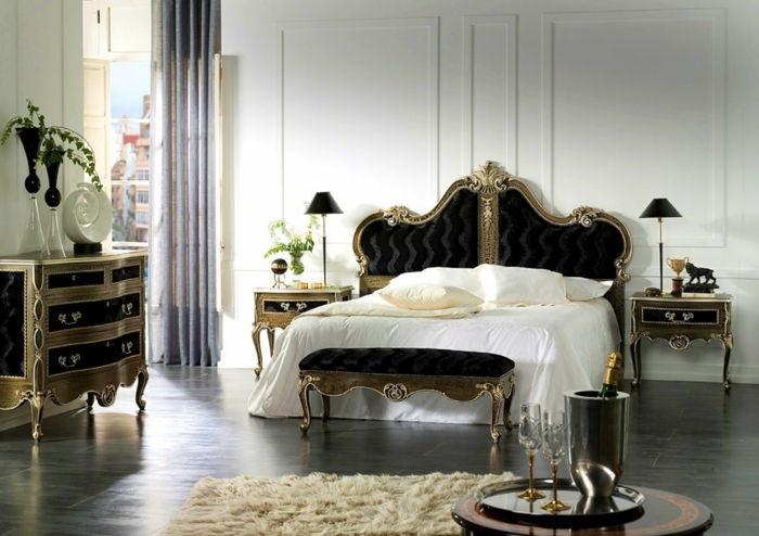 velika spalnica z zakonsko posteljo z zakonsko posteljo, gotska komoda v črni in zlati barvi, sivo bela preproga