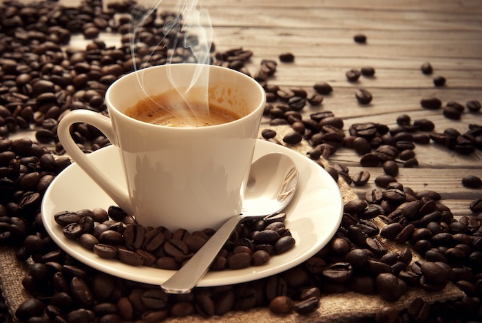Günaydın kahve - etrafında kahve çekirdekleri ile ahşap bir masa üzerinde sütlü kahve