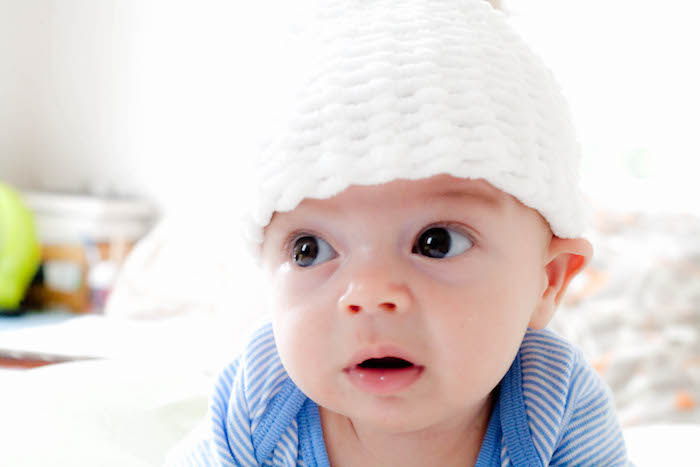 büyük kahverengi gözleri ve sevimli beyaz örgü şapka ile küçük bir bebek - güzel bir günaydın