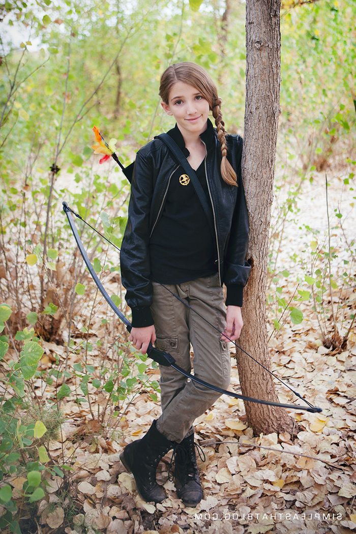 majhna deklica z lokom in oblačili Jägerja prikazuje Katniss - otroške junake